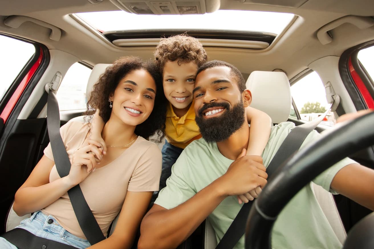 Família sorrindo abraçada dentro do carro em viagem